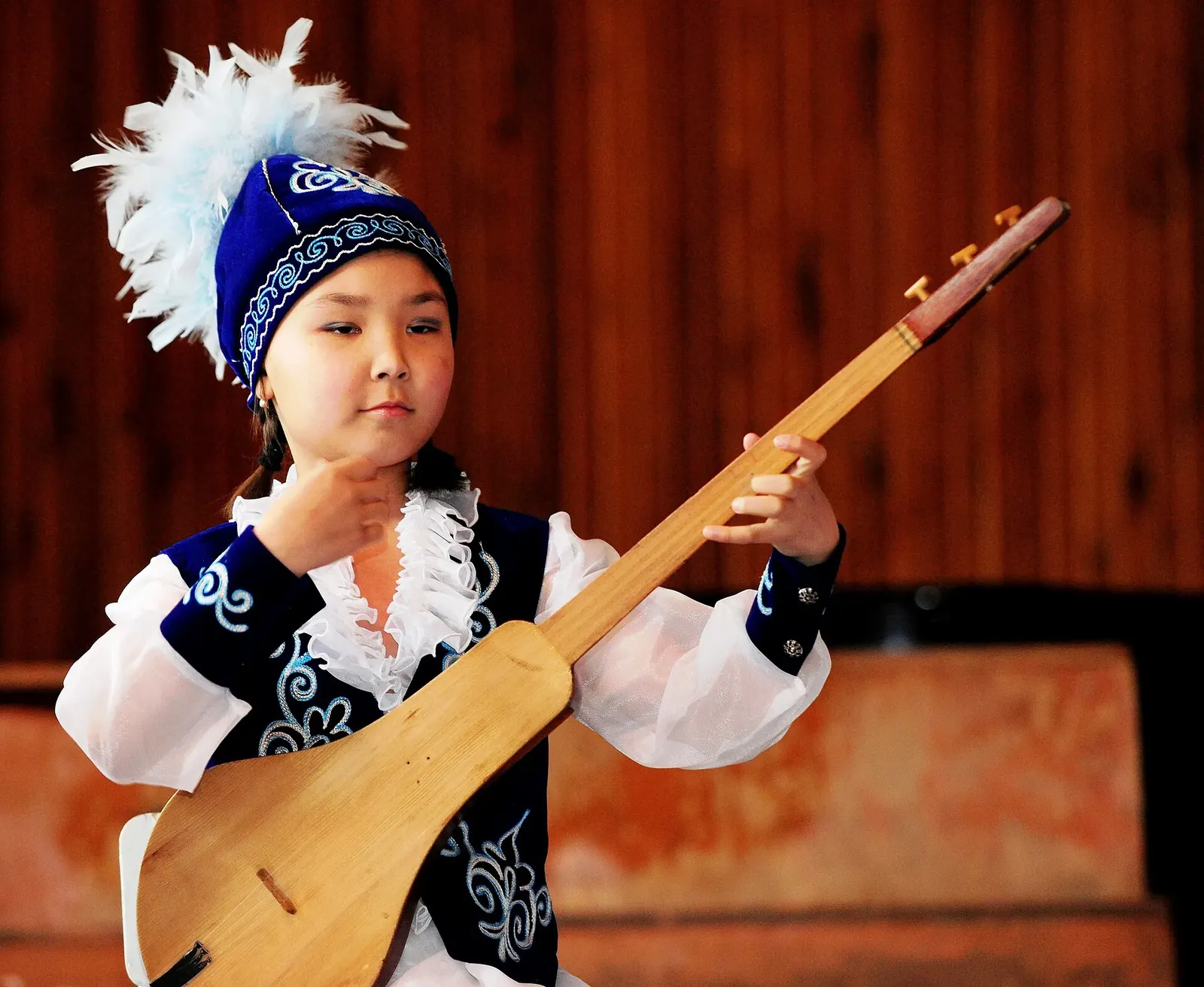 A young girl plays the Komuz, a Kyrgyz traditional instrument, at the Abdraev Musical Boarding School in Bishkek, Kyrgyzstan, Jan. 27, 2010.. Фото: Nichelle Anderson, U.S. Air Force, Public domain, Викисклад