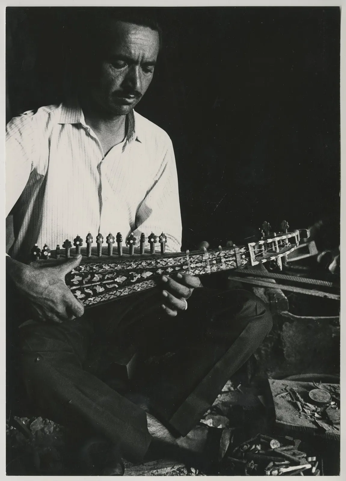 Sitzender Mann Instrumentebauer zupft eine Laute (afghanische Rubab).. Фото: Maeder, Herbert, 1930–2017, CC BY-SA 4.0, Викисклад